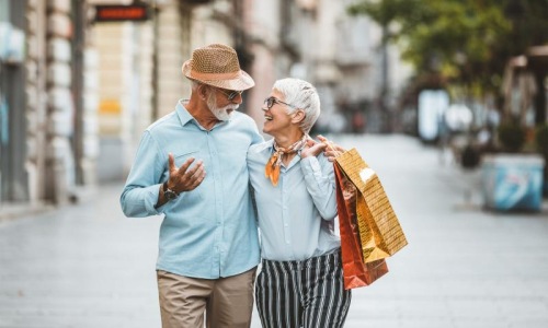 a man and woman holding shopping bags while walking